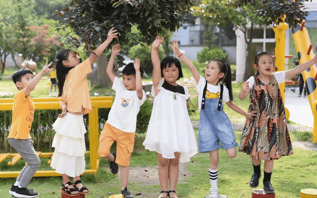 Group of children holding hands and jumping on round stepping posts at a sunny outdoor playground.